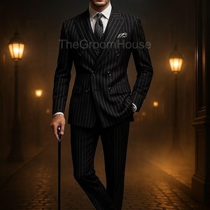 Puede incluir: Un traje negro de raya diplomática con camisa blanca, corbata negra y pañuelo de bolsillo. El traje es cruzado y la persona sostiene un bastón negro. El texto "The Groom House" es visible.