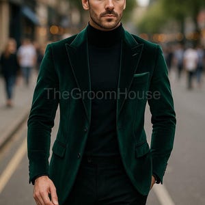 Könnte beinhalten: Ein dunkelgrüner Samtblazer mit passendem Rollkragenpullover und schwarzer Hose. Der Blazer hat ein klassisches Zwei-Knopf-Design und ein fallendes Revers. Das GroomHouse-Logo ist auf der Jacke sichtbar.