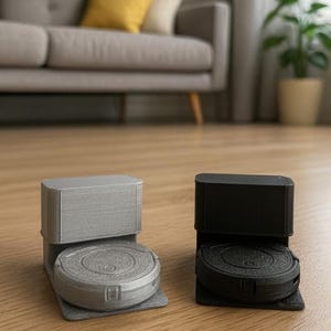 May include: Two robot vacuum cleaners, one silver and one black, sit on a wooden floor. The silver vacuum has a textured finish, while the black one is smooth. Both have a square charging base and a circular body.