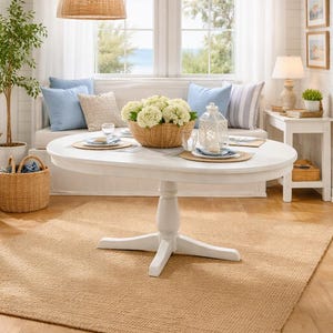 Puede incluir: Comedor luminoso y espacioso con una mesa redonda blanca, una lámpara colgante tejida y una alfombra beige. La mesa está puesta con platos y un centro de mesa de flores blancas en una cesta tejida. Se ven cojines azules y un banco.