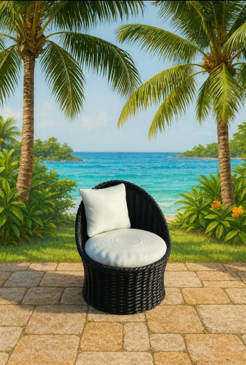 May include: A black wicker chair with a white cushion and pillow sits on a stone patio. Palm trees and a tropical beach scene with blue water and sky are in the background. The chair is designed for outdoor use.
