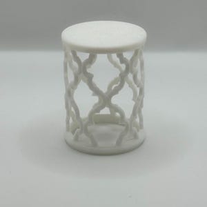 Pu&ograve; includere: Tavolino decorativo bianco, con piano rotondo e design traforato a griglia sui lati. Il tavolino &egrave; alto circa 25 cm e ha un diametro di 20 cm, adatto per esporre piccoli oggetti.