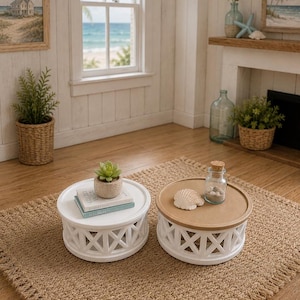 May include: Two small, round white tables with a decorative lattice base sit on a woven jute rug. One table has a succulent and books, the other a seashell and a glass jar. The tables are in a coastal-themed room.
