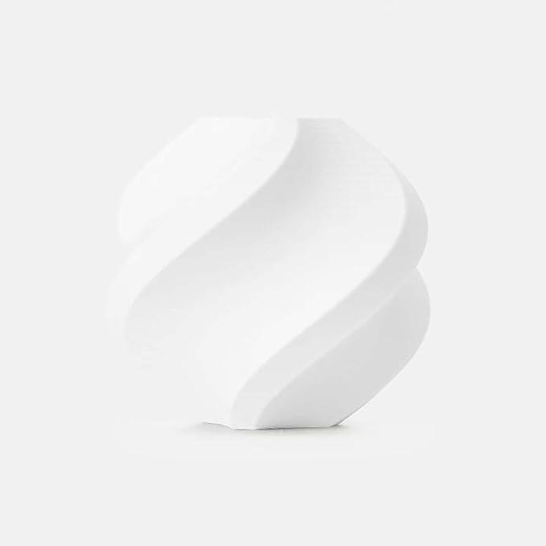 May include: A white, sculptural vase with a unique, swirling design. The vase has a smooth, matte finish and a modern aesthetic. The form is reminiscent of a twisted ribbon or a stylized flower, adding a touch of elegance to any space.