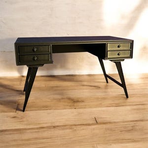May include: A black metal desk with two drawers on each side. The desk has a rectangular top and angled legs. The drawers have small, round knobs. The desk is set on a wooden floor.