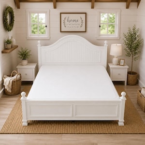 May include: A white wooden bed frame with a matching headboard and footboard. The bed is made up with a white sheet. A framed sign that reads "home is my favourite place to be" hangs above the bed. The bed sits on a woven rug.