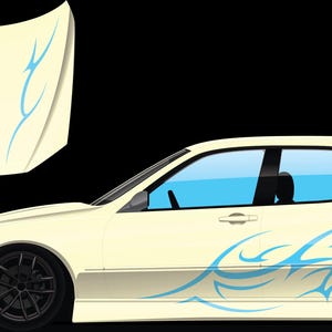 Pode incluir: Sedan creme com rodas pretas e vidros azuis fumados. O carro apresenta decalques de chamas tribais azuis na lateral e no capô. O capô está solto e exibido separadamente.
