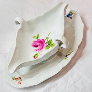 Può includere: Servizio di salsiera e piatto in porcellana bianca. La salsiera presenta una rosa rosa con foglie verdi e un bordo strutturato. Il piatto ha un bordo strutturato abbinato e decorazioni floreali. Il set è progettato per servire salse.