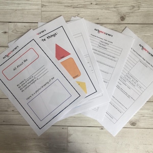 Op de afbeelding: Een stapel witte papieren vellen met tekst en afbeeldingen, waaronder de woorden "All About Me" en "'te things:" in rood en zwart. De vellen liggen op een licht houten oppervlak.