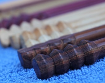 May include: Close-up of a set of wooden dowels with different coloured finishes. The dowels are arranged in a row, with the darkest dowel in the foreground. The dowels are on a blue fuzzy surface.