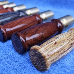 May include: Close-up of six wooden handles with different wood grain patterns and metal caps. The handles are arranged in a row on a blue surface.