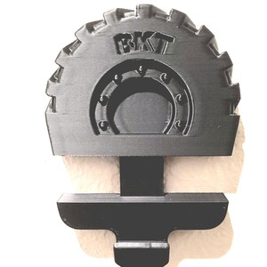 May include: A black, gear-shaped object with the letters "BKT" at the top. The object has a semi-circular design in the center and a rectangular base. The object is likely a mechanical part or component.