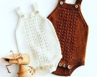 May include: Two knitted baby onesies, one white and one brown, with button closures. The onesies have a delicate, lacy pattern.
