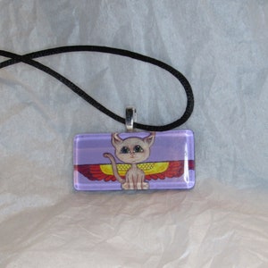 May include: A rectangular pendant necklace featuring a cartoon cat with wings on a purple background. The cat is light gray with large eyes, and the wings are red and yellow. The pendant is attached to a black cord.