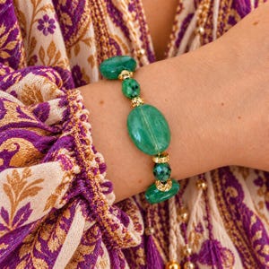 Peut inclure: Un bracelet composé de perles de pierre vertes lisses et facettées, alternées avec de petites entretoises en métal doré texturé. Le design comprend une grande perle ovale verte centrale, des perles facettées plus petites et des perles rondes.