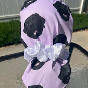 Peut inclure: Une coiffe de chirurgien lilas avec un motif répété de visages de Labrador Retriever noirs. Le bonnet est rassemblé à l'arrière avec un chouchou en satin blanc. Le bonnet est conçu pour les professionnels de la santé ou de la beauté.