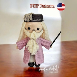 Pode incluir: Boneca de crochê de um mago com barba branca longa, óculos e varinha. A boneca usa um casaco rosa e um chapéu escuro. A imagem inclui o texto "PDF Pattern" e uma bandeira dos EUA.