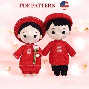 May include: Two crocheted dolls dressed in red traditional outfits, holding hands. The dolls have black hair and are wearing matching hats. The text "PDF PATTERN" is at the top of the image. The dolls are holding a flower.