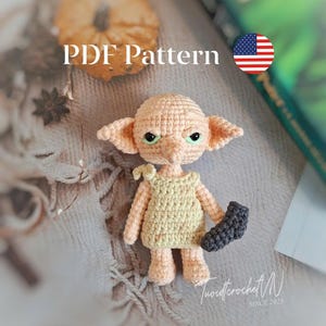 May include: A crocheted doll with large ears, green eyes, and a yellow dress, holding a dark gray sock. The doll is on a textured surface. The text "PDF Pattern" is visible. The image includes a small American flag.