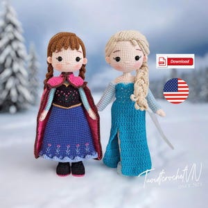 May include: Two crocheted dolls, one with brown hair in braids wearing a blue dress and pink cape, and the other with blonde hair in a braid wearing a blue dress. The dolls are standing in a snowy landscape.