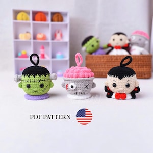 Puede incluir: Tres adornos de ganchillo: un monstruo verde con pelo negro, una criatura gris con cerebro y un ojo, y un vampiro con pelo negro y pajarita roja. Cada figura tiene un pequeño lazo negro o rosa en la parte superior. Texto: PDF PATTERN.