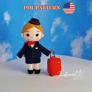 May include: A crocheted doll of an airline stewardess in a navy blue uniform, red scarf, and hat, holding a red suitcase. The doll has blonde hair and black shoes. The image includes the text "PDF PATTERN" and an American flag.