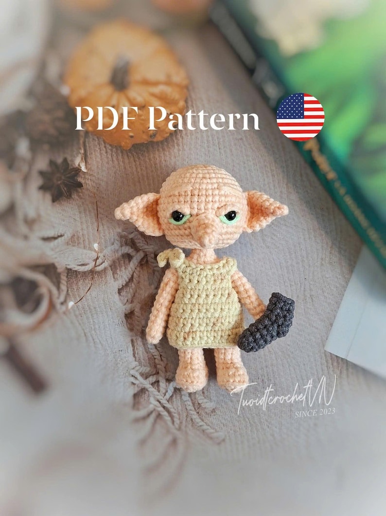 May include: A crocheted doll with large ears, green eyes, and a yellow dress, holding a dark gray sock. The doll is on a textured surface. The text "PDF Pattern" is visible.