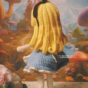 May include: A handmade crochet doll of a character with yellow hair, a blue dress, and black shoes. The doll is positioned in front of a whimsical background. The text "MADE BY MY LOVELY CUSTOMER" is visible.