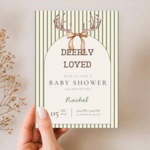 May include: A rectangular baby shower invitation card featuring a cream-colored center with an arched border and green vertical stripes on the sides. The top displays watercolor deer antlers with a tan ribbon. Text reads: DEERLY LOVED, JOIN US FOR A BABY SHOWER, CELEBRATING, Rachel, 05 SEP 2024, 3:00 PM - 5:00 PM, 123 Anywhere St., Any City.