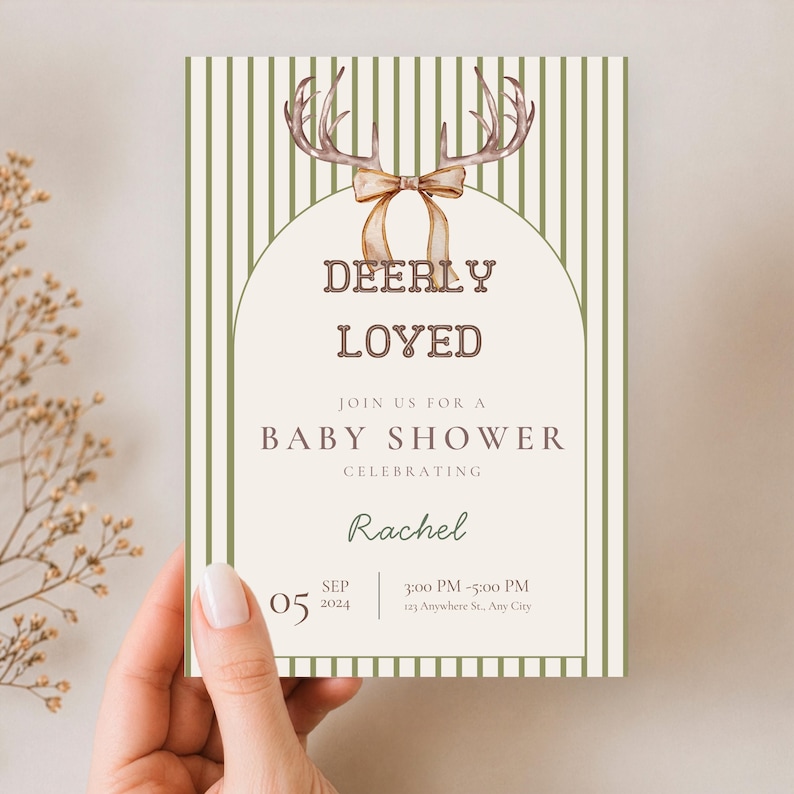May include: A rectangular baby shower invitation card featuring a cream-colored center with an arched border and green vertical stripes on the sides. The top displays watercolor deer antlers with a tan ribbon. Text reads: DEERLY LOVED, JOIN US FOR A BABY SHOWER, CELEBRATING, Rachel, 05 SEP 2024, 3:00 PM - 5:00 PM, 123 Anywhere St., Any City.
