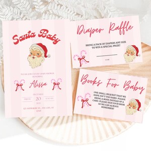 May include: Pink baby shower invitations with a Santa theme. The invitation includes the text "Santa Baby" and "Diaper Raffle". The design features a Santa Claus illustration and candy cane accents. The invitation is on a light pink background.