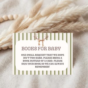 May include: A rectangular card with a white center and olive green vertical stripes. The text reads: BOOKS FOR BABY. ONE SMALL REQUEST THAT WE HOPE ISN'T TOO HARD. PLEASE BRING A BOOK INSTEAD OF A CARD. PLEASE SIGN YOUR BOOK SO WE CAN ALWAYS REMEMBER!