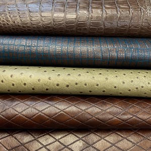 May include: Close-up of several textured leather samples in various colors. The top sample is a brown crocodile pattern, followed by a teal grid design, a light green ostrich pattern, and a brown diamond pattern. The bottom sample is a dark brown embossed design.