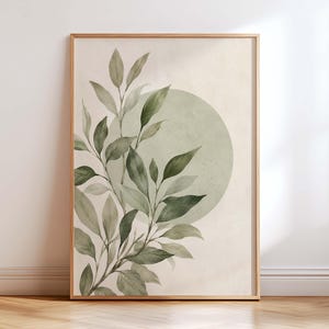 May include: A framed wall art print featuring a watercolor illustration of green leafy branches extending from the bottom left corner across a large, pale sage green circle set against a neutral, off-white background within a thin wooden frame.