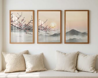 May include: Three framed landscape prints with a serene mountain scene. The artwork features a soft color palette of beige, pink, and gray, with cherry blossoms in the foreground. The frames are a warm brown color, and the prints are displayed above a bench with pillows.