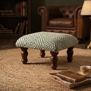 May include: A square footstool featuring a green and white diamond-patterned woven fabric top supported by four dark brown turned wooden legs. The footstool has a firm, padded seat and a low profile, providing a stable base for resting feet.