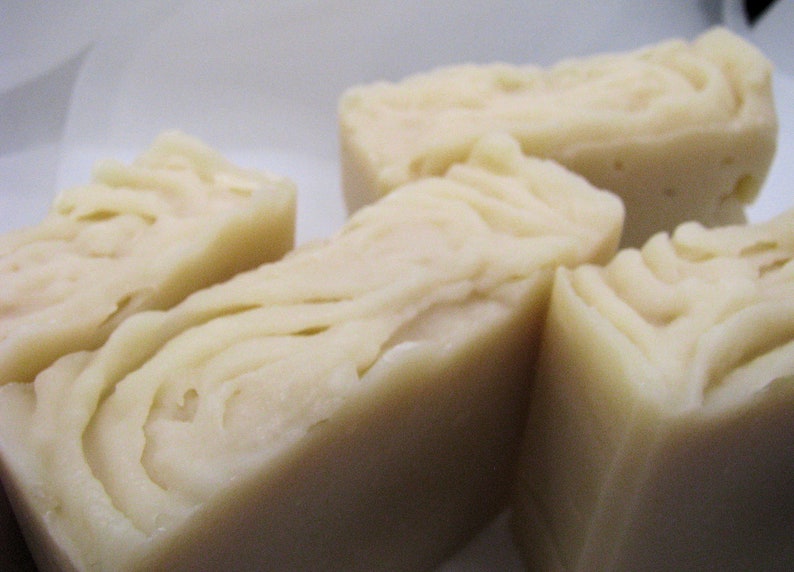 May include: Four bars of white soap with a swirl pattern. The soap is arranged in a row on a white surface.