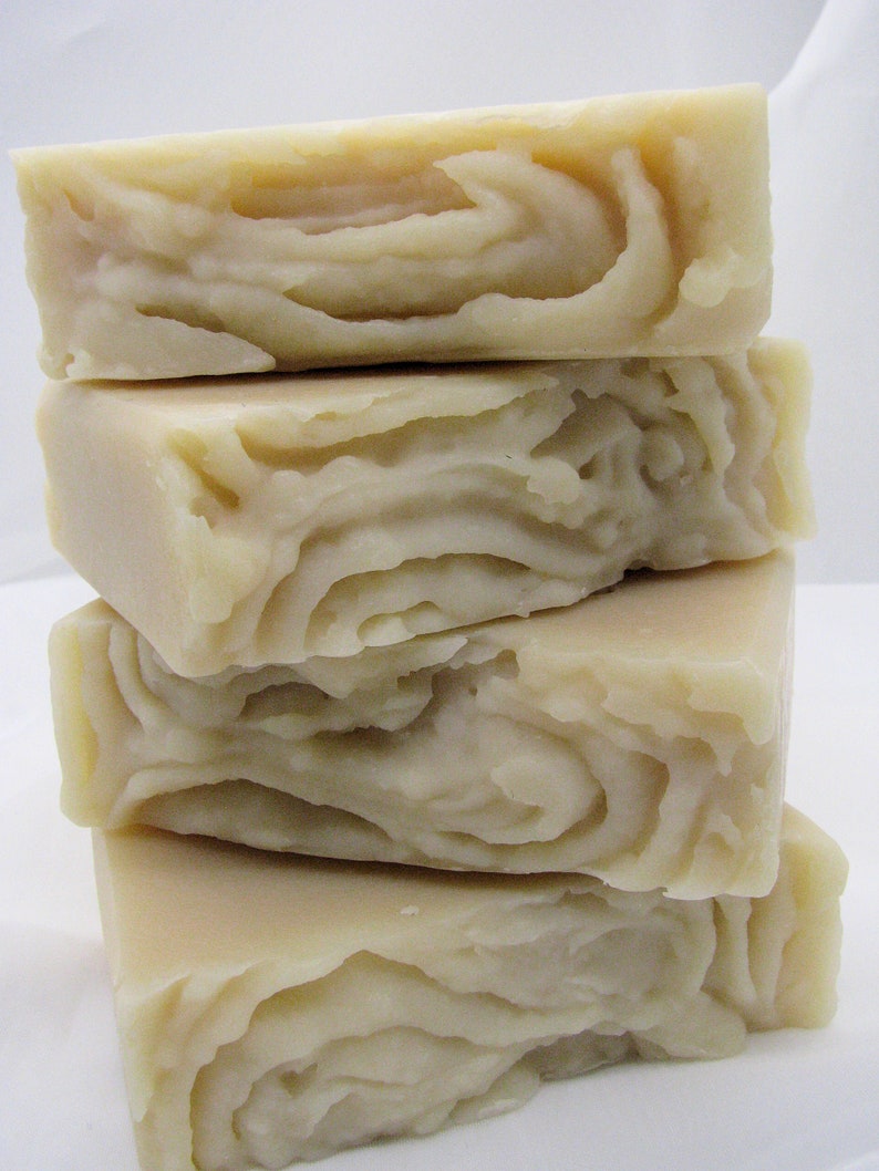 May include: Four bars of handmade soap stacked on top of each other. The soap is a light beige color and has a swirl pattern.