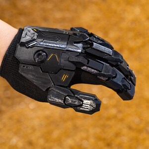 Cyberpunk Mecha Gloves shown in an action pose on a cosplayer’s hand, emphasizing the dynamic futuristic look and advanced mechanical structure ideal for immersive roleplay, sci-fi performances, and dystopian photo sessions. The 3D printed exoskeleton armor showcases complex paneling, raised textures, and articulated knuckles that create a realistic robotic appearance.