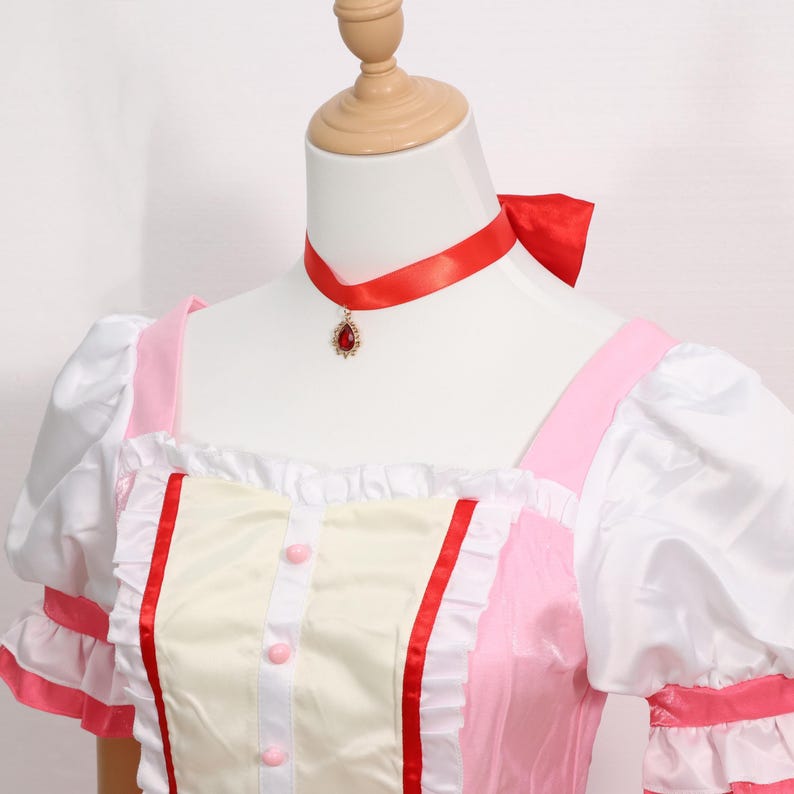 Detail shot of the accessories included with the Madoka Kaname cosplay set: matching gloves, pink choker with red gem, white socks, and decorative headwear. Each accessory is made to match the anime’s character design, offering a complete transformation into Madoka Kaname. Suitable for cosplay festivals, anime conventions, and as a gamer gift for fans of platform-style magical girl games. An excellent costume for collectors or performers.