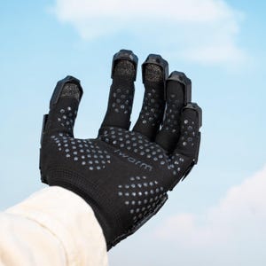 K&ouml;nnte beinhalten: Schwarzer Arbeitshandschuh mit strukturierten Grip-Punkten und verst&auml;rkten Fingerspitzen. Auf dem Handschuh steht das Wort "warm" auf dem Handgelenk. Der Hintergrund ist ein blauer Himmel.