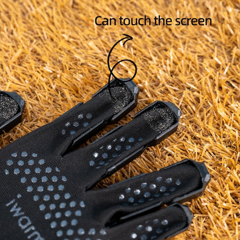 K&ouml;nnte beinhalten: Nahaufnahme von schwarzen Handschuhen mit gepunktetem Muster und dem Text "iWarm". Die Fingerspitzen haben ein Mesh-Design, und der Text "Can touch the screen" ist sichtbar. Die Handschuhe liegen auf einer braunen, stroh&auml;hnlichen Oberfl&auml;che.