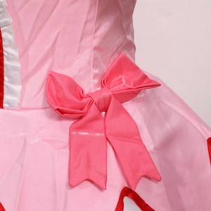 Detail shot of the accessories included with the Madoka Kaname cosplay set: matching gloves, pink choker with red gem, white socks, and decorative headwear. Each accessory is made to match the anime’s character design, offering a complete transformation into Madoka Kaname. Suitable for cosplay festivals, anime conventions, and as a gamer gift for fans of platform-style magical girl games. An excellent costume for collectors or performers.