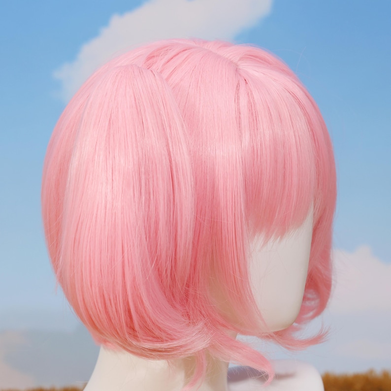 Close-up view of the Madoka Kaname pink twin tails cosplay wig showing the high-quality synthetic matte fiber texture and vibrant color. The wig is styled for anime accuracy, including parted bangs and curled twin tail tips. This heat-resistant wig is perfect for conventions, cosplay birthday gifts, holiday celebrations, platform gaming enthusiasts, and anyone looking to bring Madoka’s magical girl spirit to life.