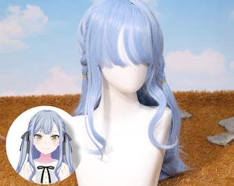 May include: A light blue wig with long, wavy hair and bangs, styled with two side braids secured with gold bands. The wig is displayed on a white mannequin head. A small illustration of a character with the same hairstyle is in the corner.