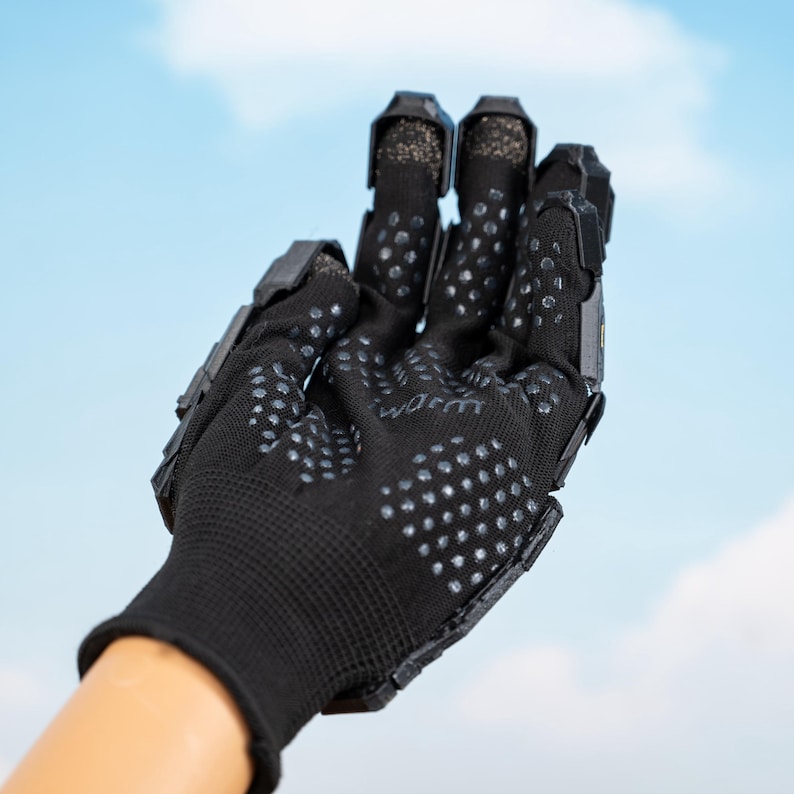 K&ouml;nnte beinhalten: Schwarzer Handschuh mit strukturierter Handfl&auml;che und Fingerschutz. Der Handschuh hat ein netzartiges Gewebe und ist mit kleinen, grauen, rutschfesten Griffen versehen. Die Finger haben einen schwarzen, starren Schutz. Auf der Handfl&auml;che steht das Wort "worm".