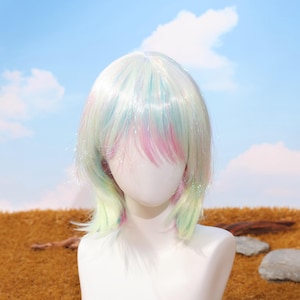 May include: A pastel-colored wig with a short, layered style. The wig features a blend of white, pink, blue, and green hues, with a slight shimmer. The wig is displayed on a mannequin head against a backdrop of a blue sky and brown field.