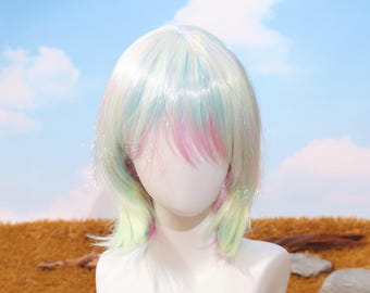 May include: A pastel-colored wig with a short, layered style. The wig features a blend of white, pink, blue, and green hues, with a slight shimmer. The wig is displayed on a mannequin head against a backdrop of a blue sky and brown field.