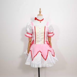 Front view of a model wearing the complete Madoka Kaname cosplay costume, highlighting the charming details of the gloves, choker, and headwear included in the set. The outfit recreates the iconic look of Madoka from Puella Magi Madoka Magica with incredible accuracy, making it ideal for fans of magical girl anime. Lightweight and available in sizes from XS to 3XL, it suits a wide range of body types for cosplay or themed holiday events.
