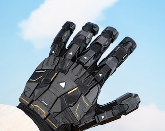 May include: A black and gold robotic glove with a complex, geometric design. The glove features segmented panels, triangular accents, and gold trim. The background is a bright blue sky with fluffy white clouds.